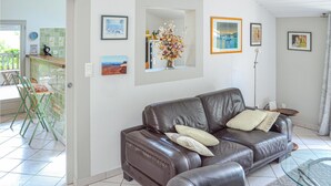 Ein Wohnzimmer mit einem braunen Ledersofa, einem Glastisch und einer Wandvase mit Blumen.