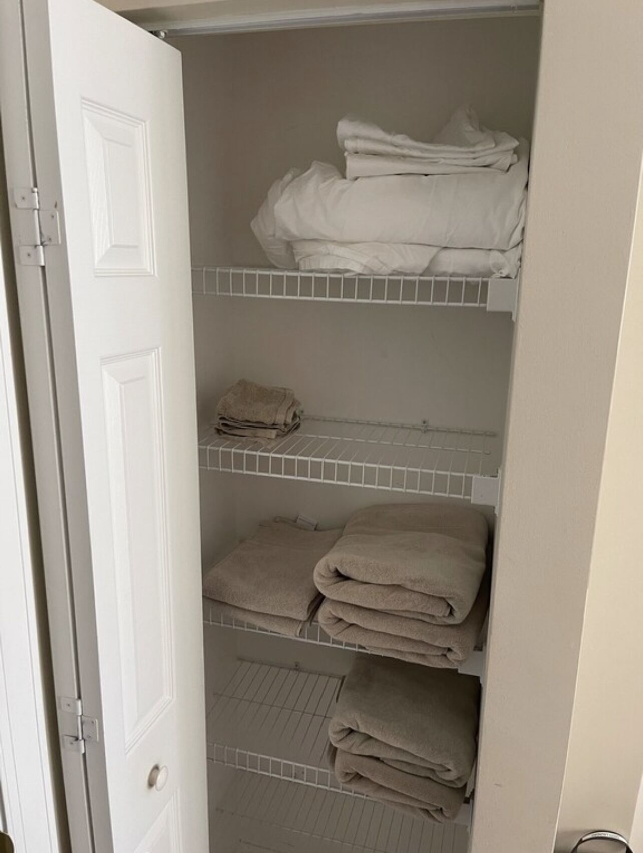 Ein Schrank mit drei Regalen, auf denen gefaltete Handtücher liegen.