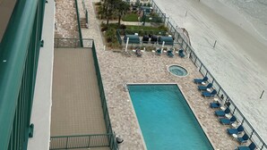 Um hotel com área de piscina, espreguiçadeiras e vista para a praia e o oceano.