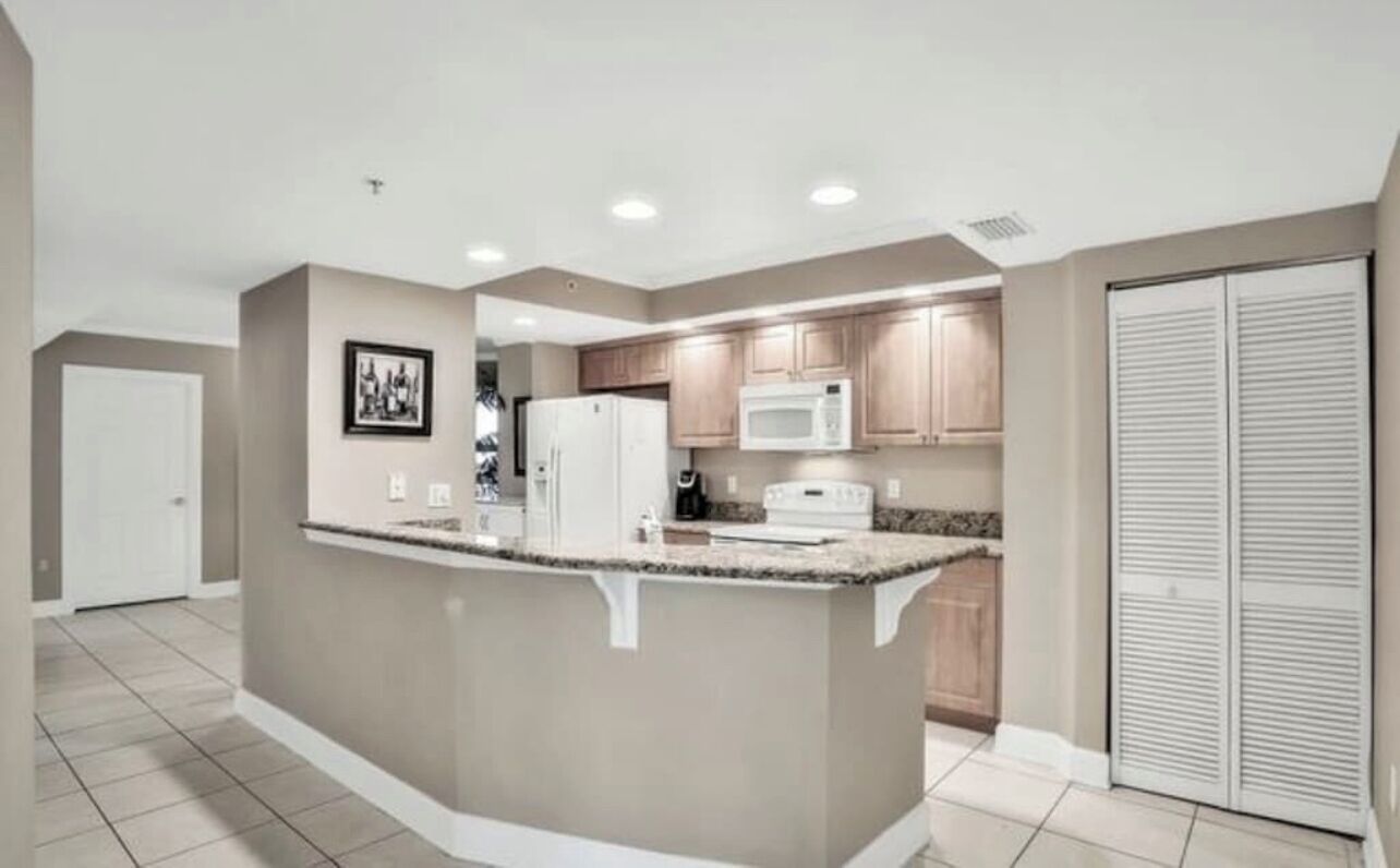 A modern kitchen with a central island, built-in microwave, and wooden cabinets.