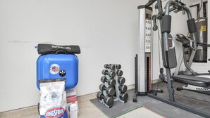 Un gimnasio con equipo de ejercicios, un depósito de agua azul y bolsas de suplementos.