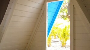 Une pièce dotée d’un plafond en pente et d’une porte-fenêtre donnant sur un espace extérieur aménagé avec des plantes.