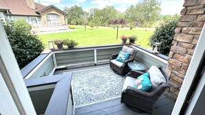 A covered porch with wicker furniture and a patterned rug.