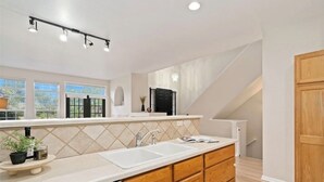 A modern kitchen with a large island, double sinks, and wooden cabinets.