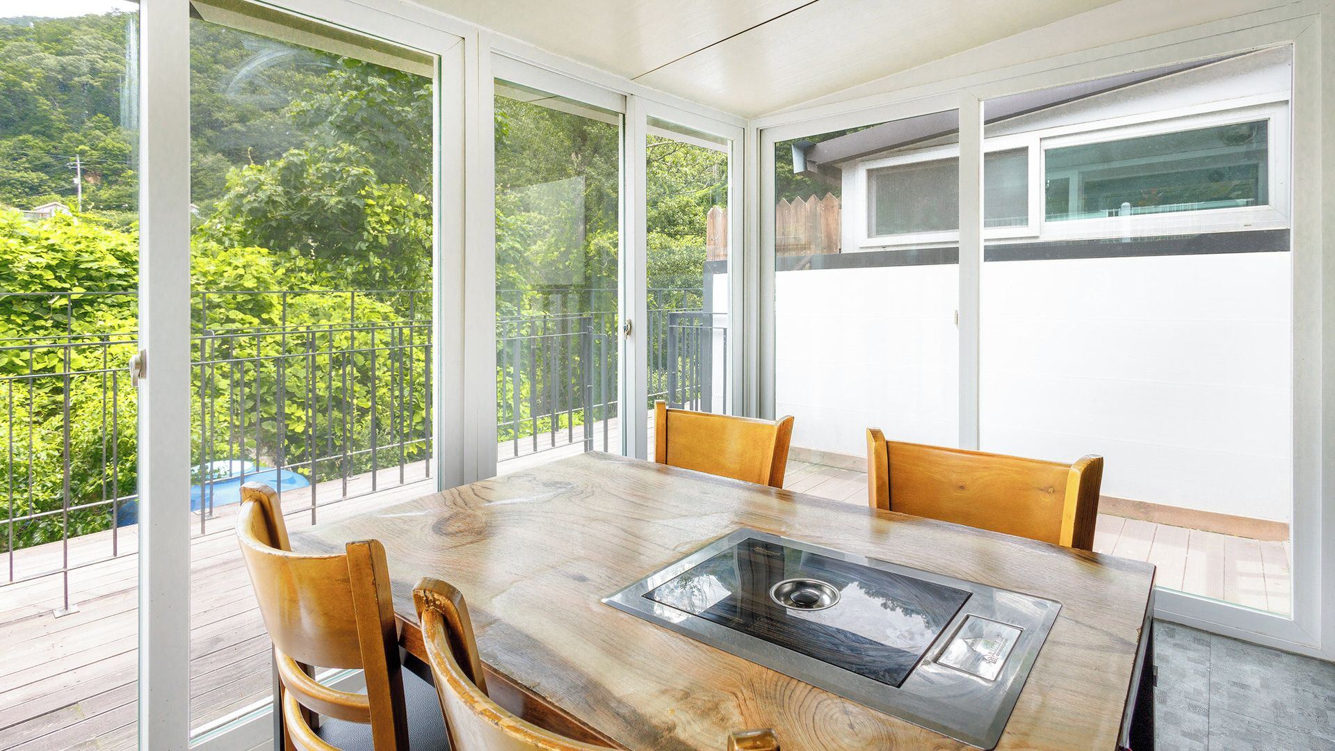 A dining area with a table and chairs, large windows, and a view of greenery.