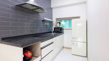 Una cocina con encimera negra, microondas, refrigerador blanco y estufa a gas.