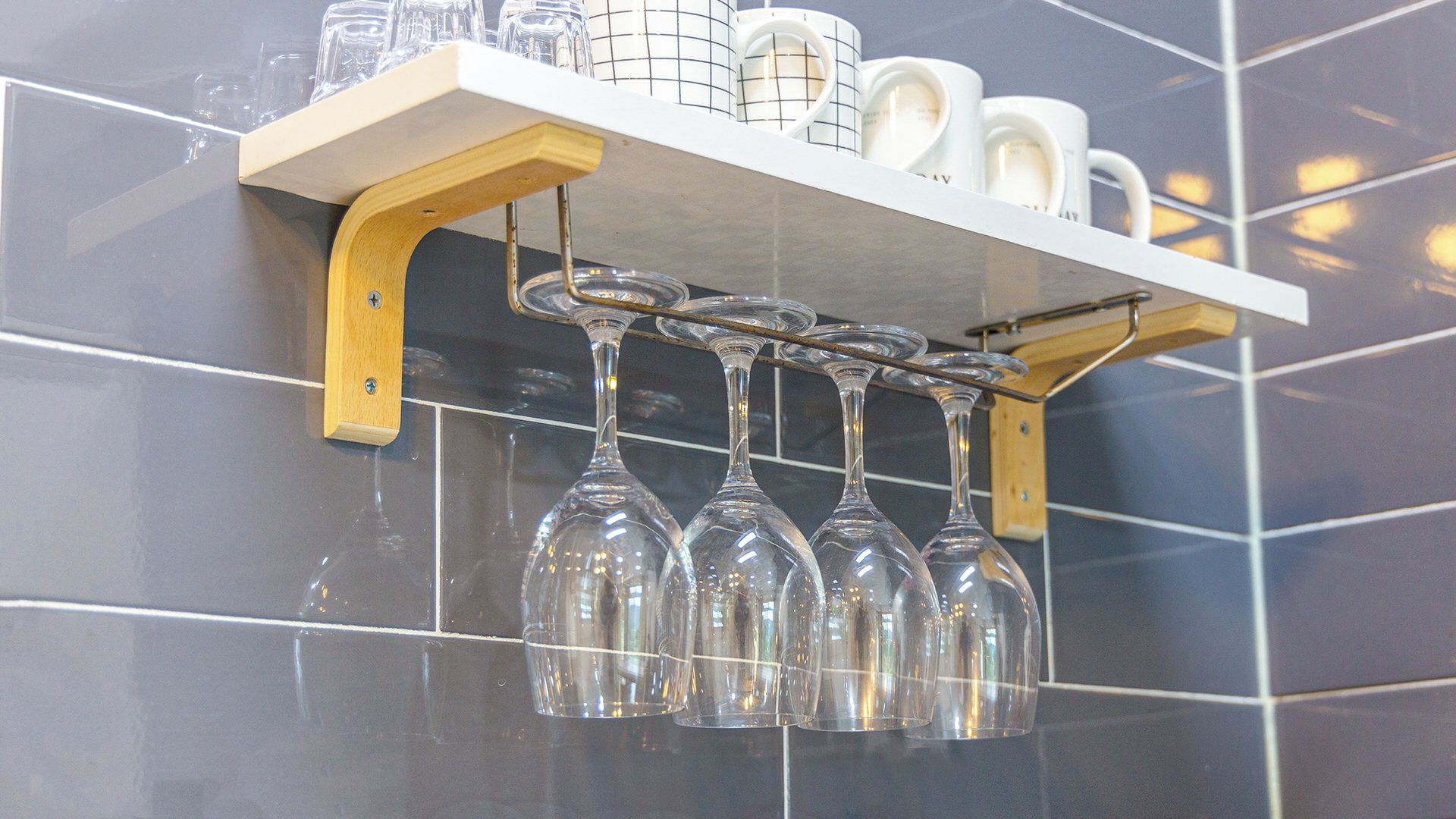 A wall-mounted shelf with wine glasses and mugs.