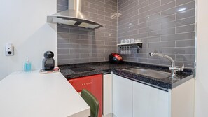 A compact kitchen with a black countertop, stainless steel sink, and a red appliance. - Gapyeong Gamseong216 Poolvilla Pension (Gapyeong)