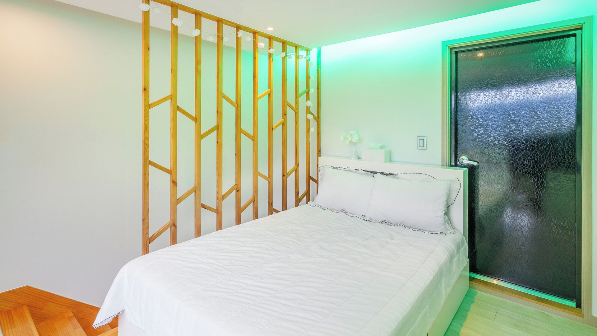 A bedroom with a bed, a window with a view, and a wooden partition.