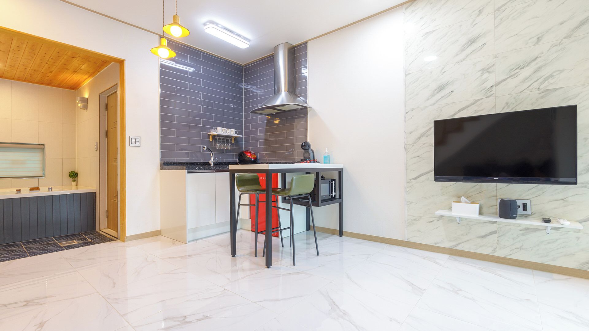 A modern kitchen with a built-in stove, a microwave, and a large flat-screen TV mounted on the wall.
