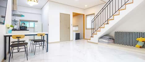 A modern interior with a kitchen, dining area, and staircase.