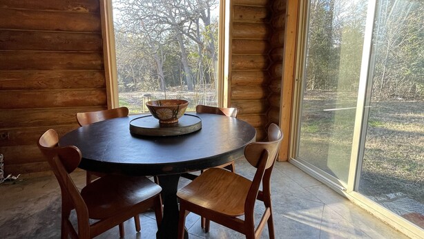 Ein Holzinterieur mit einem runden Tisch, Stühlen und einem großen Fenster.