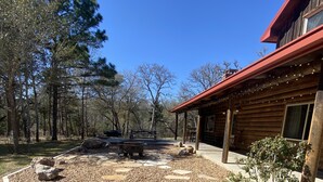 Eine rustikale Holzhütte mit einer Holzterrasse und einem Feuerkorb in der Mitte.
