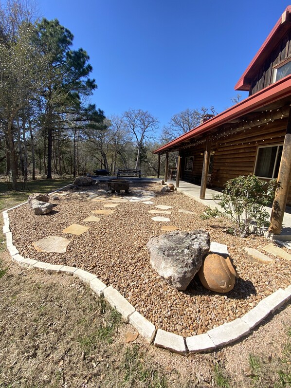 A rustic cabin with a wooden deck and a fire pit in the center. - Paradise at Bucek Lane (Schulenburg)