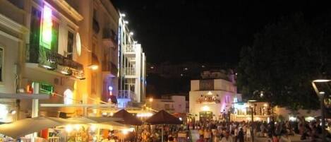 A bustling street scene at night with shops and people.