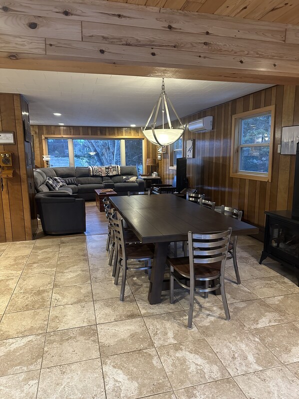 Un salon chaleureux avec un grand canapé d’angle, une table à manger avec des chaises et une cheminée.