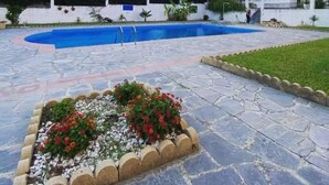 A swimming pool with a stone deck and a flower bed with red flowers. - Kallithea - Apartment - Stay 2 - Parking - Seaside (Kallithea)