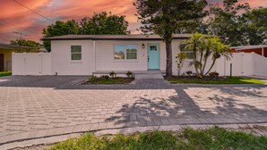 A single-story house with a light blue door, a small front yard with a palm tree, and a paved driveway. - Charming Centrally Located, 3 bedroom house! (Tampa)