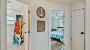 A hallway with a shower, a bed with a blue and white patterned bedspread, and a wooden wall decoration. - Charming Centrally Located, 3 bedroom house! (Tampa)