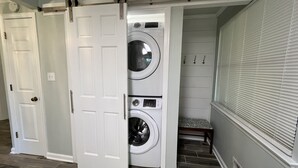 A laundry room with a front-loading washer and dryer, a sliding door, and a bench. - Cheerful, relaxing ranch in quiet neighborhood with fire pit (Newton)