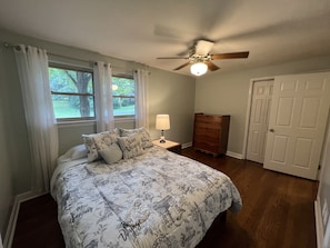 A bedroom with a bed, a nightstand, a dresser, a ceiling fan, and a window with curtains. - Cheerful, relaxing ranch in quiet neighborhood with fire pit (Newton)