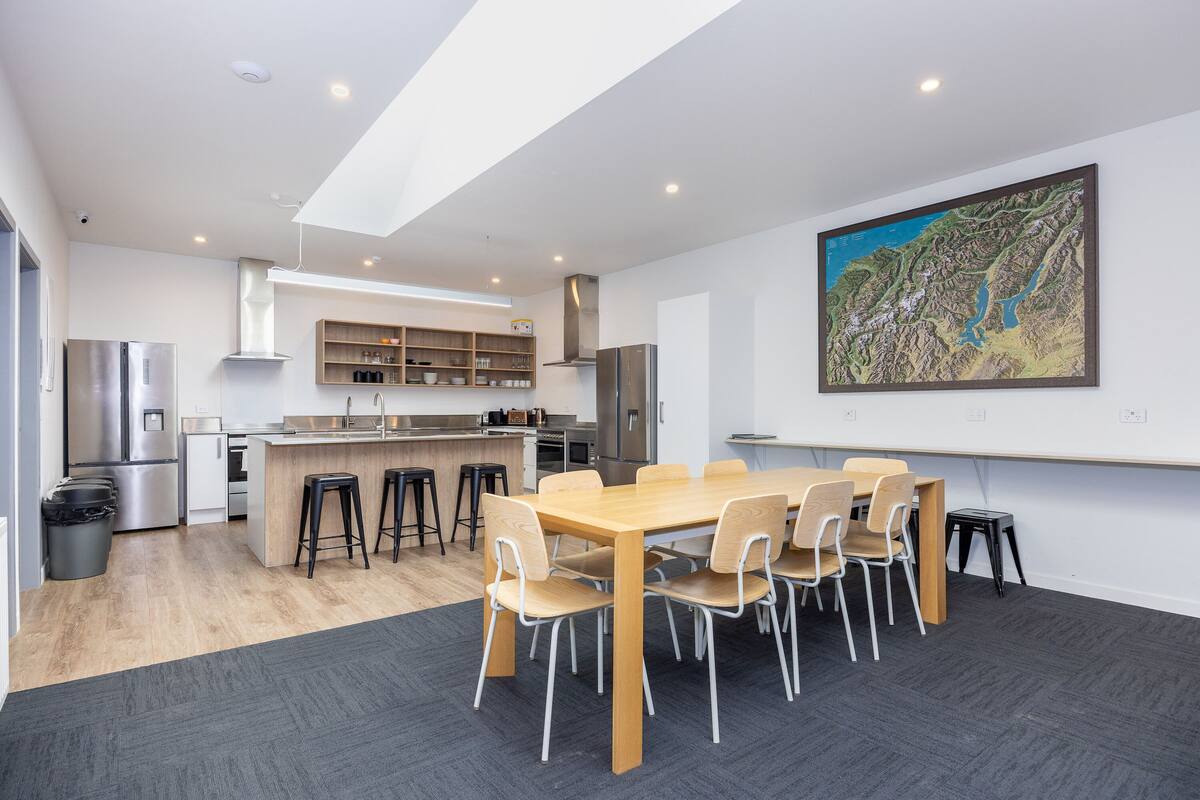 A modern kitchen with a central island, bar stools, and a dining table with chairs.