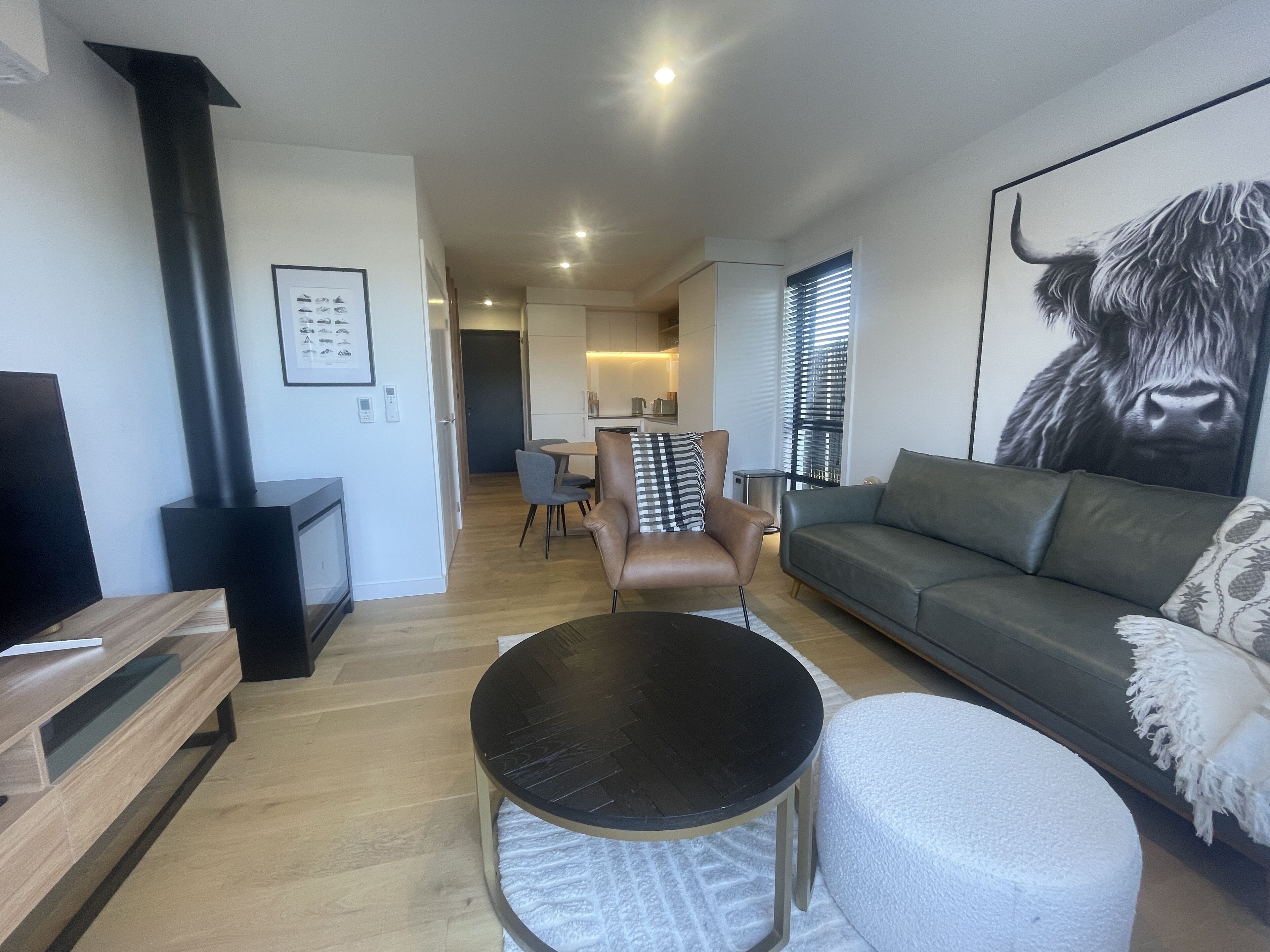 Una sala de estar moderna con un sofá, una mesa de centro, una chimenea y un comedor al fondo.
