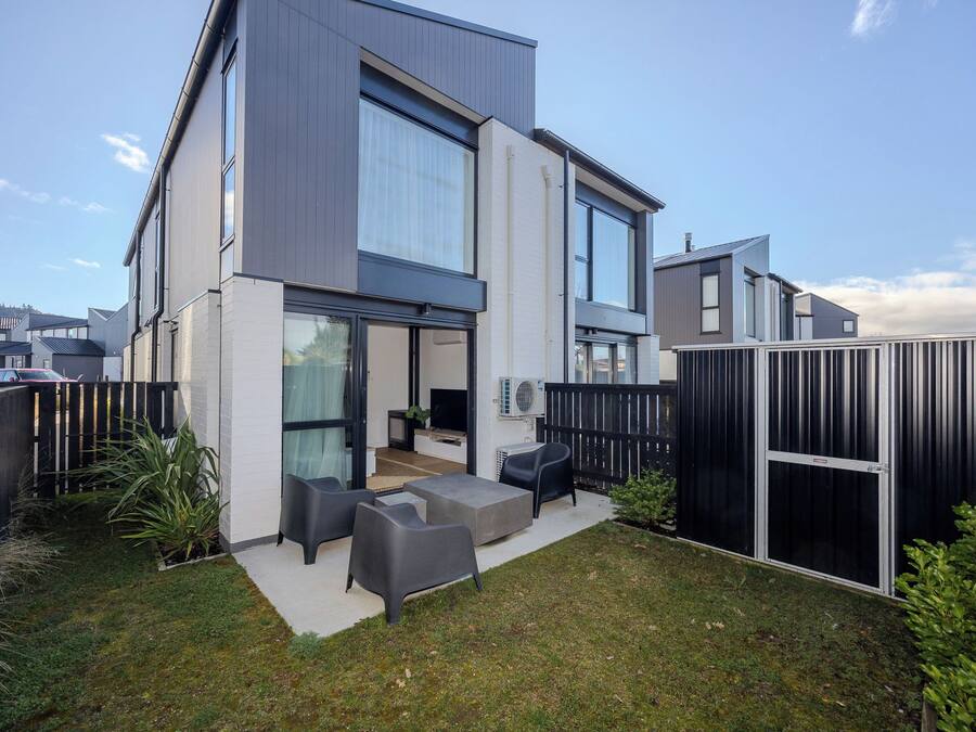 Una casa moderna de dos pisos con un patio amoblado al aire libre.