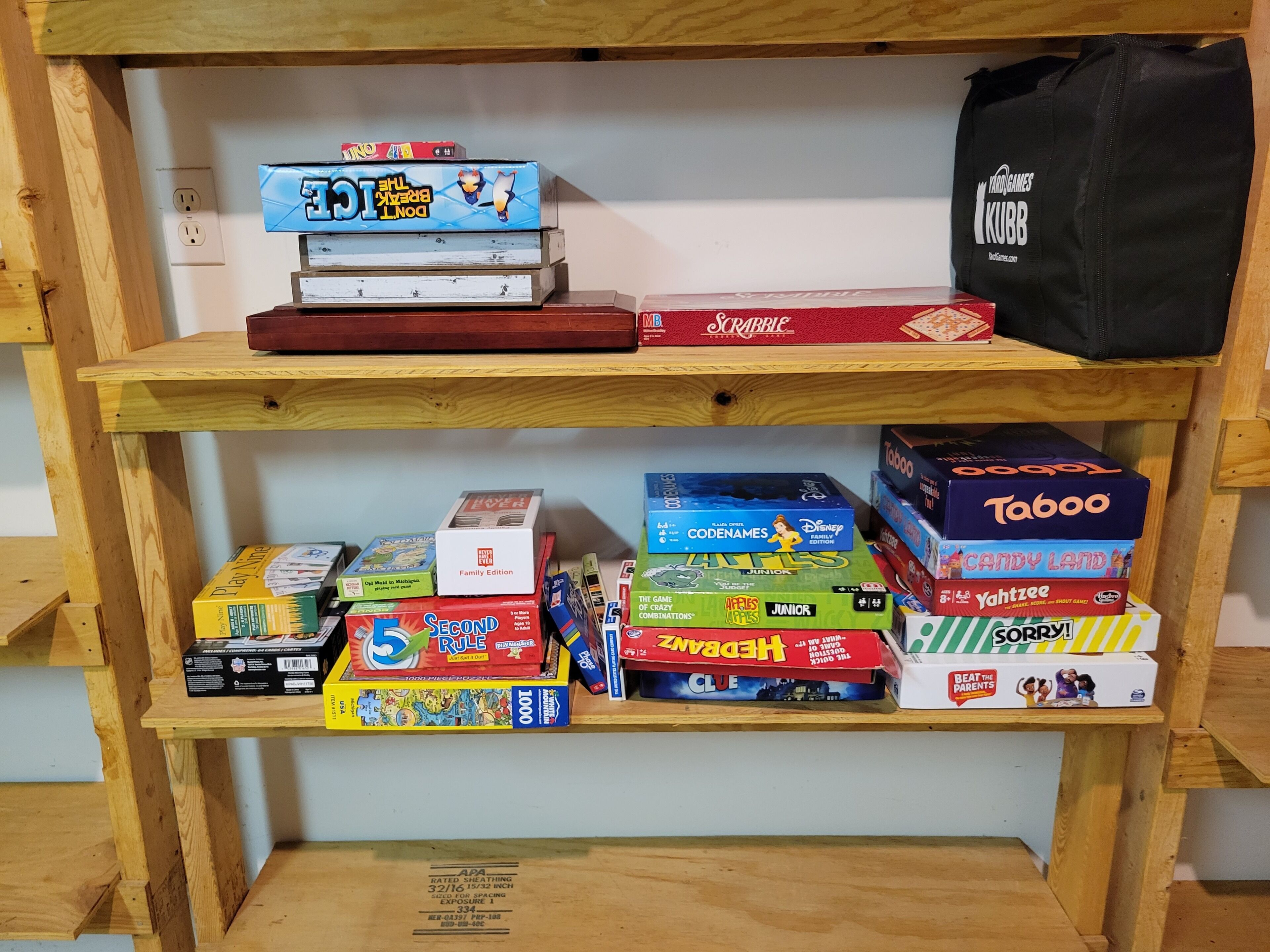 Uma estante com vários jogos de tabuleiro, incluindo Scrabble, Taboo e Candy Land.