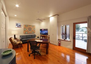 A spacious living room with a dining area, a gray sofa, a TV, and a view of the outdoors.
