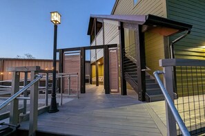 A wooden deck with a metal railing, a staircase, and a building entrance. - Custom Shed #1 in Berry Hill off 8th—Step-Free (Nashville)