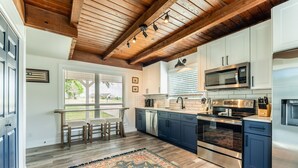 Una cocina moderna con vigas de madera, electrodomésticos de acero inoxidable y un ventanal grande.