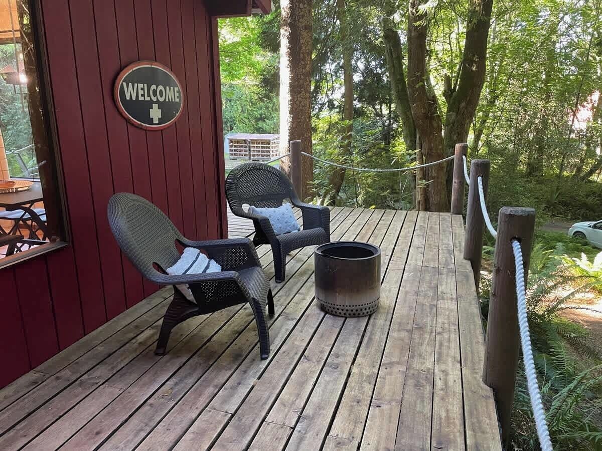 A wooden deck with two wicker chairs and a metal container. A 'WELCOME' sign is visible on the wall.