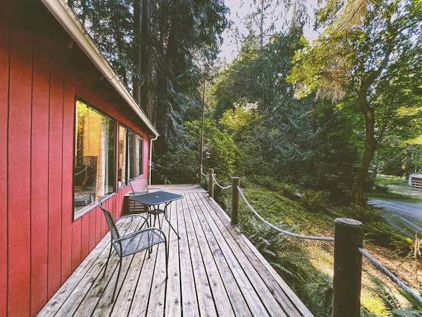 Ein rotes Gebäude mit einer Holzdiele und einem Tisch mit Stühlen.
