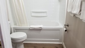 A bathroom with a toilet, a bathtub, and a shower curtain. - Richard Lake Motel (Sudbury)