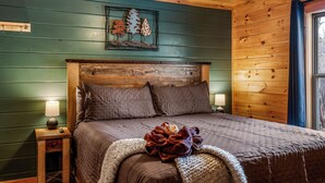 Ein Schlafzimmer in einer Holzhütte mit einem Bett, Nachttischen und einem Wandbild.