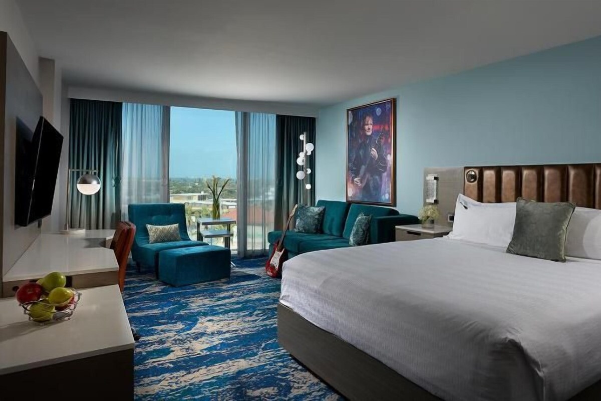 Une chambre d’hôtel avec un grand lit, un bureau, une chaise et une vue sur l’extérieur.