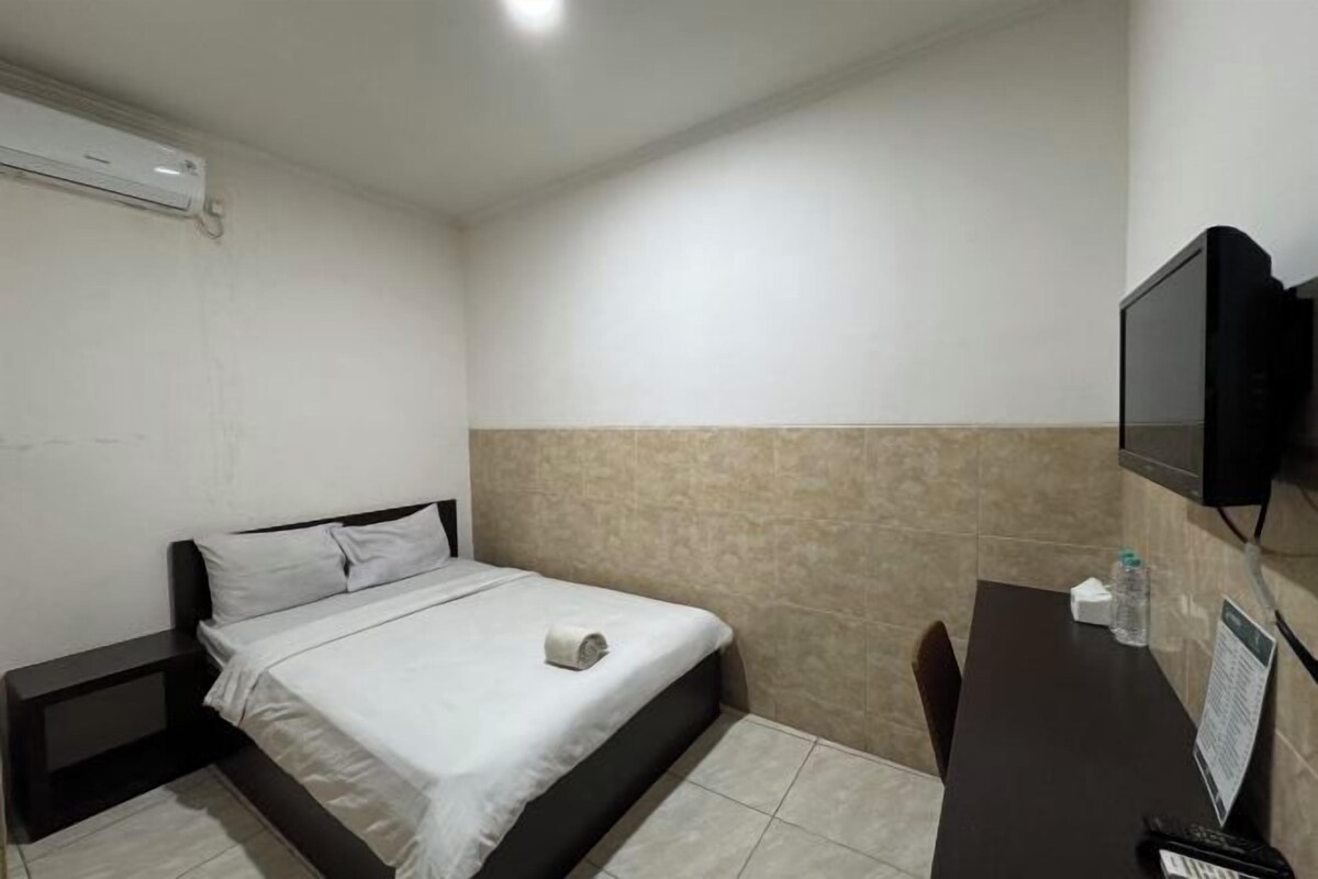Une chambre d’hôtel équipée d’un lit, d’un bureau, d’une chaise, d’une télévision et d’un climatiseur fixé au mur.