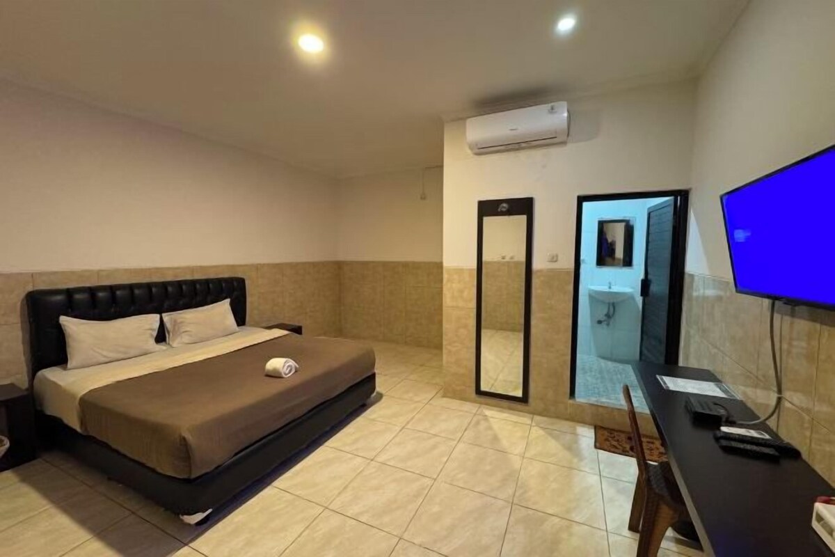 Une chambre d’hôtel équipée d’un lit, d’un bureau, d’une télévision, d’un miroir et d’un appareil de climatisation.