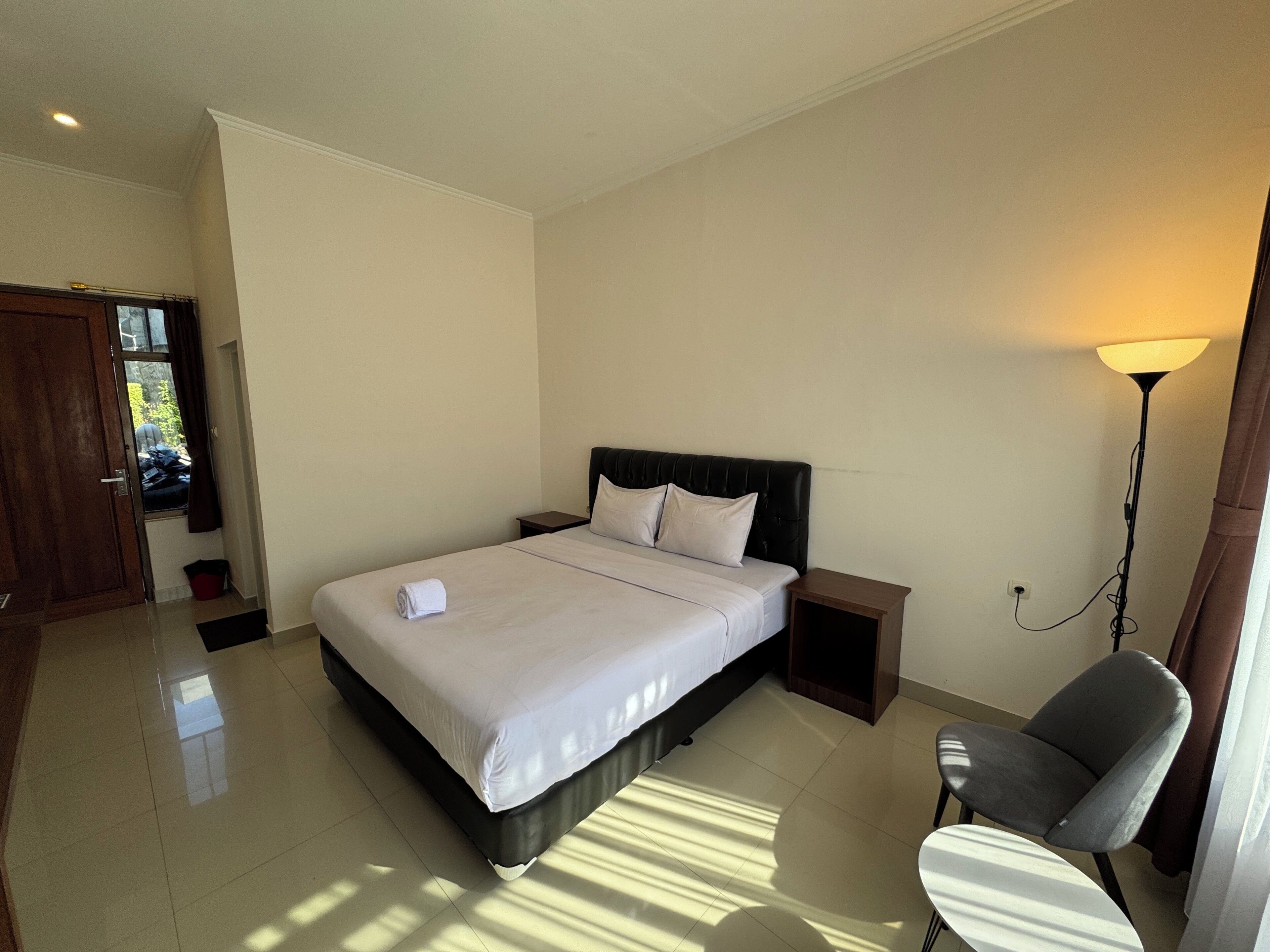 Een slaapkamer met een bed, nachtkastjes, een stoel, een lamp en uitzicht op het omliggende landschap.
