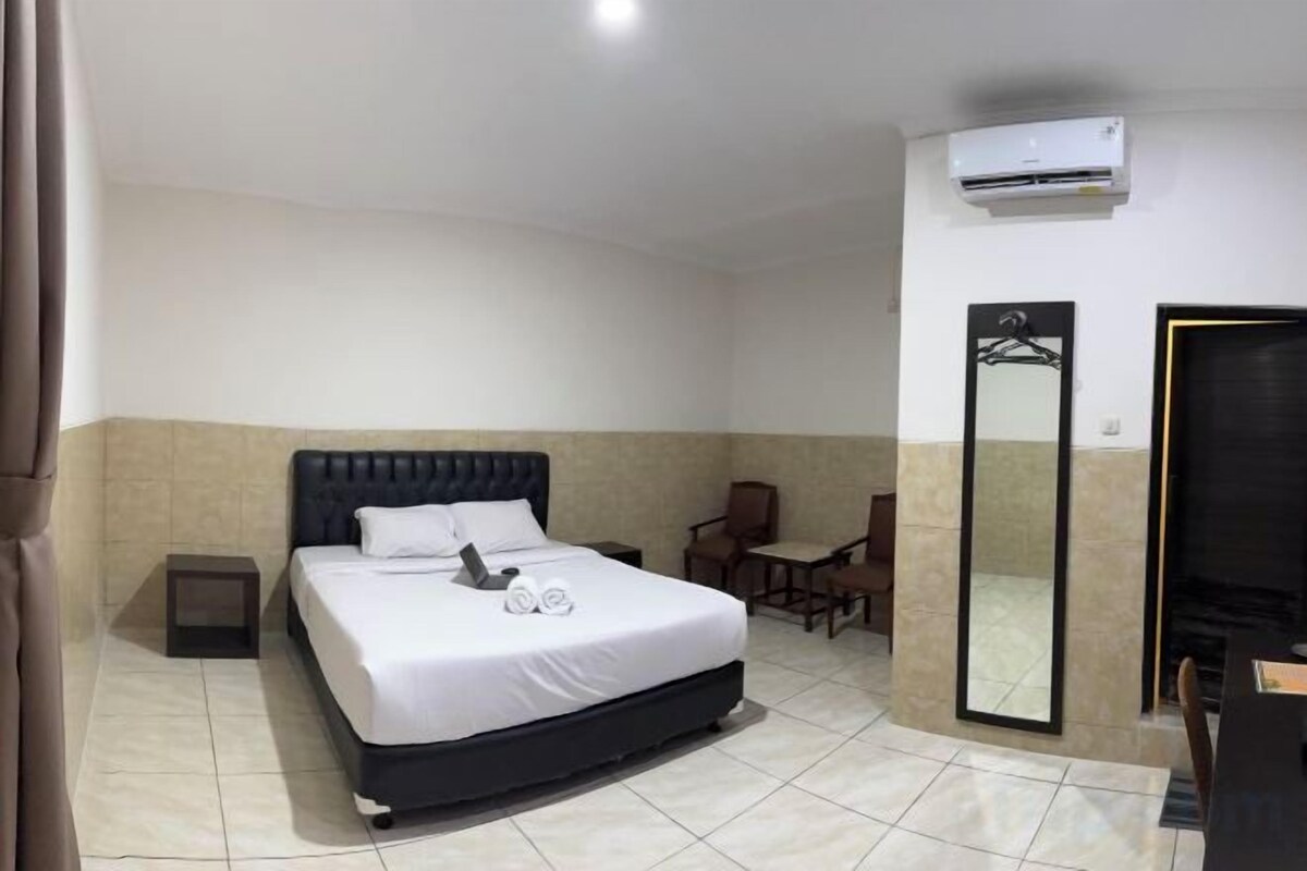 Une chambre d’hôtel équipée d’un lit, d’une chaise, d’un bureau, d’un miroir et d’un appareil de climatisation.