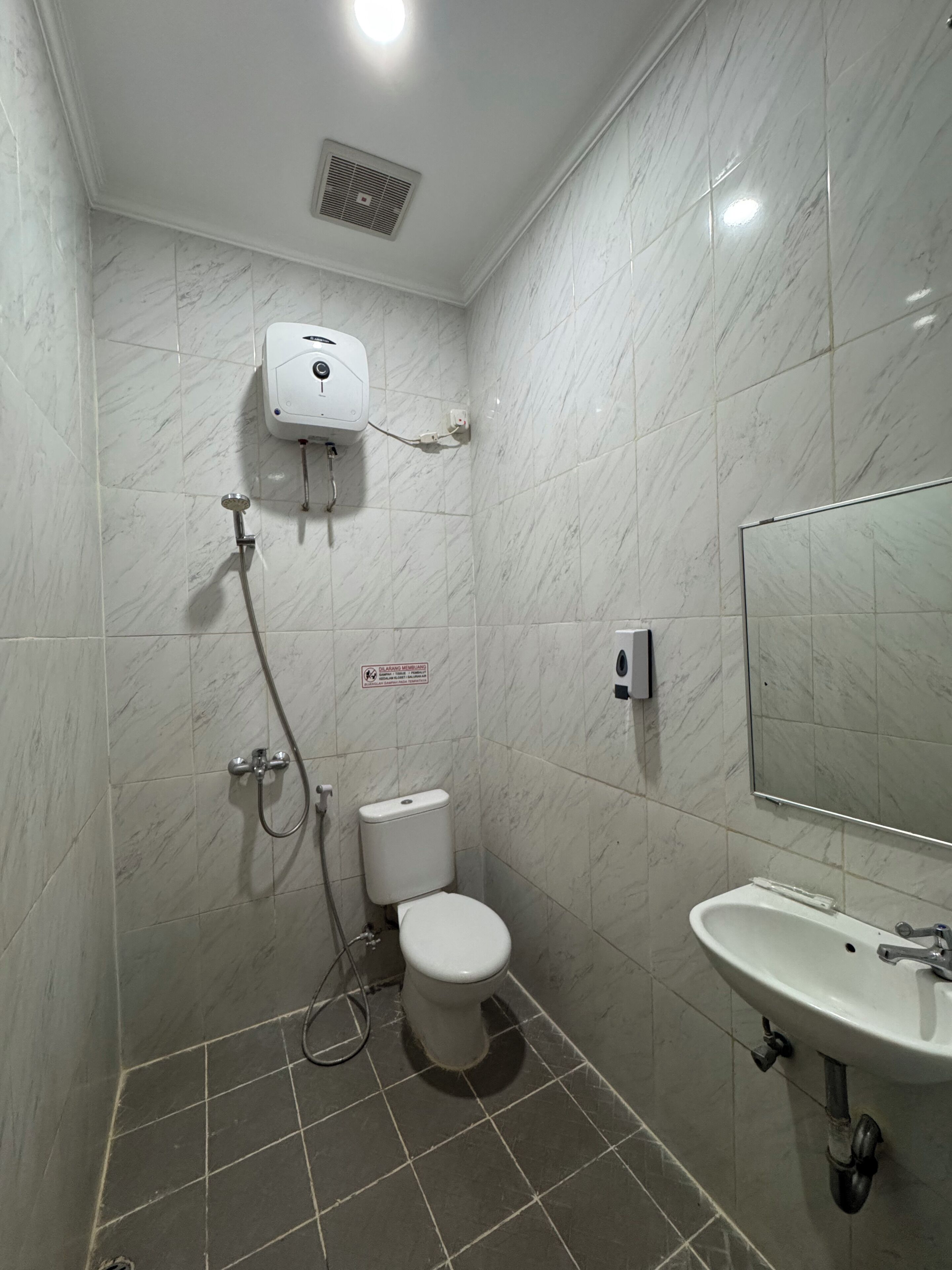 A small bathroom with a toilet, a shower, and a sink.