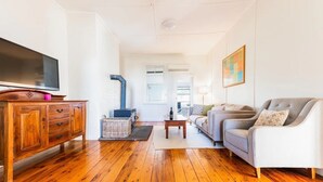 Un salon avec un plancher en bois, un canapé, une télévision et une cheminée.