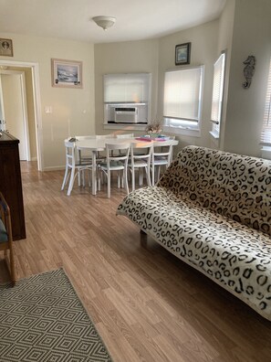 A living room with a white sofa, a dining table with chairs, a wooden floor, and a fireplace. - 4.5 blocks to beach. Huge yard (Wildwood)