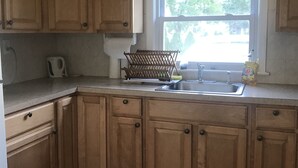 Une cuisine avec des meubles de rangement en bois, une fenêtre et un évier.
