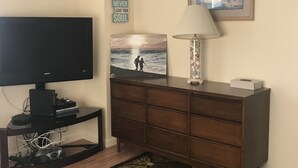 Un salon comprenant un téléviseur, une lampe, un tableau encadré et des œuvres d’art murales à caractère motivant.