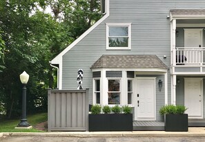A two-story house with a grey exterior, a front porch, and a small balcony.