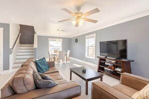 A modern living room with a sofa, coffee table, TV stand, and a ceiling fan.