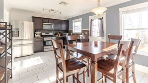 A modern kitchen with dark cabinets, stainless steel appliances, and a wooden dining table with chairs. - Spacious 3 BR • Convenient • Big Yard • Office (Kyle)