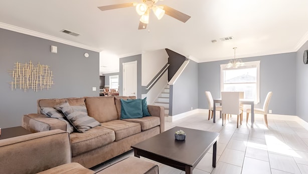 A modern living room with a brown sectional sofa, a dark coffee table, and a dining area with a white table and chairs. - Spacious 3 BR • Convenient • Big Yard • Office (Kyle)